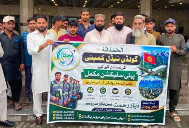 Workers and Diyar-e-Rehmat team at the airport holding a Golden Needle selection banner before departing for Kyrgyzstan