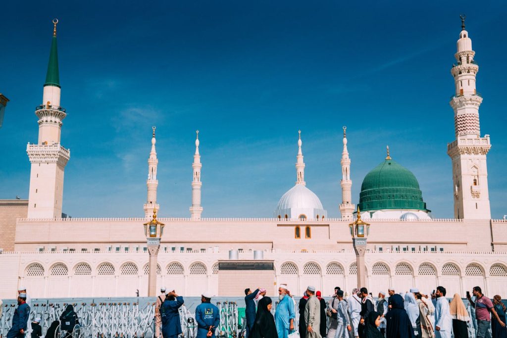 Crowds gather outside the majestic Prophet's Mosque on a sunny day in Medina, Saudi Arabia.