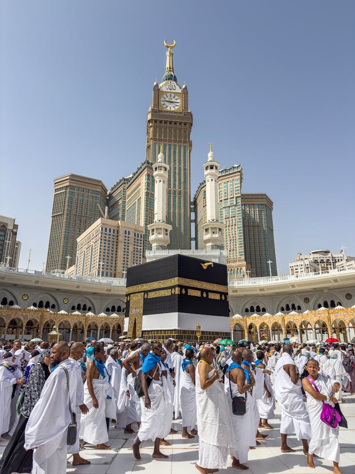 pexels-photo-32290182 A large group of pilgrims gather at the Kaaba in Mecca, Saudi Arabia, during the Hajj pilgrimage under a clear blue sky.